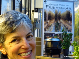 Lori in front of a Friðheimar sign, a pot of soup, and basil plants